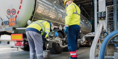 Deux opérateurs portant des équipements de protection jaune, des casques et des masques à la station de déchargement des camions. Deux opérateurs portant des équipements de protection jaune, des casques et des masques à la station de déchargement des camions.